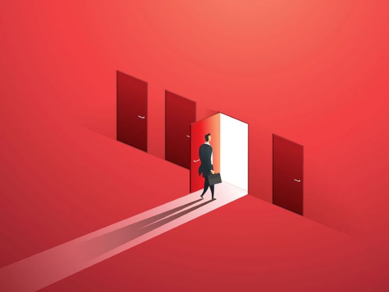 Businessman walking through open door along red wall of doors