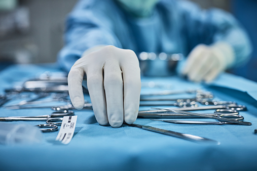 A surgeon reaching for medical equipment